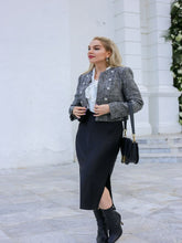 A lady wears a tweed jacket and a black skirt.